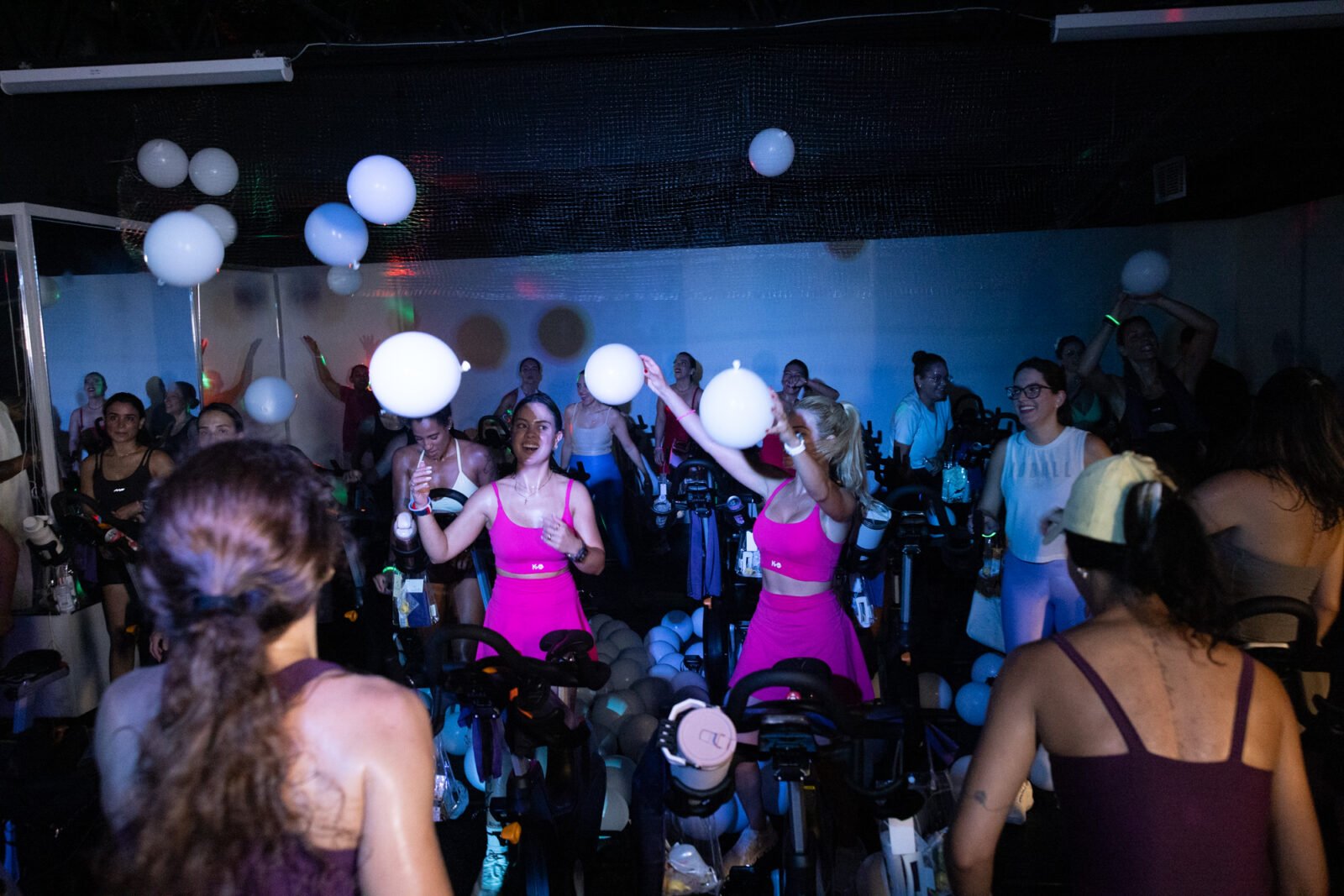 The balloon drop: riders in hot pink reach up to catch white balloons falling over the bikes